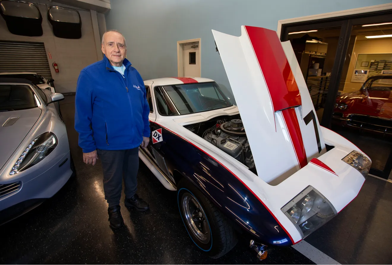 Bob Caruso standing beside a classic Corvette inside the Billy Bob's shop.