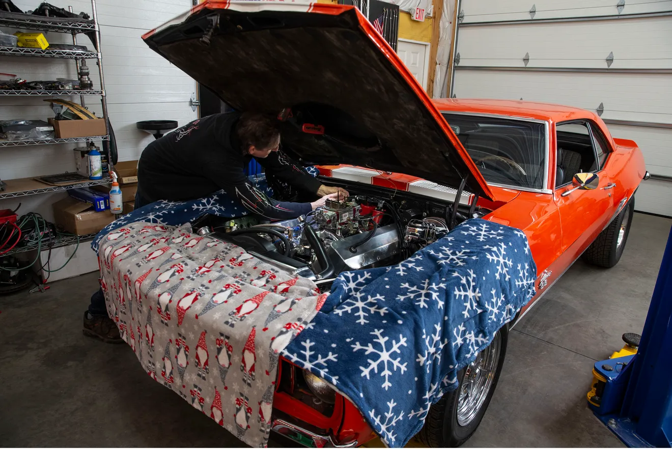 Classic orange muscle car being worked on inside the Billy Bob's shop.